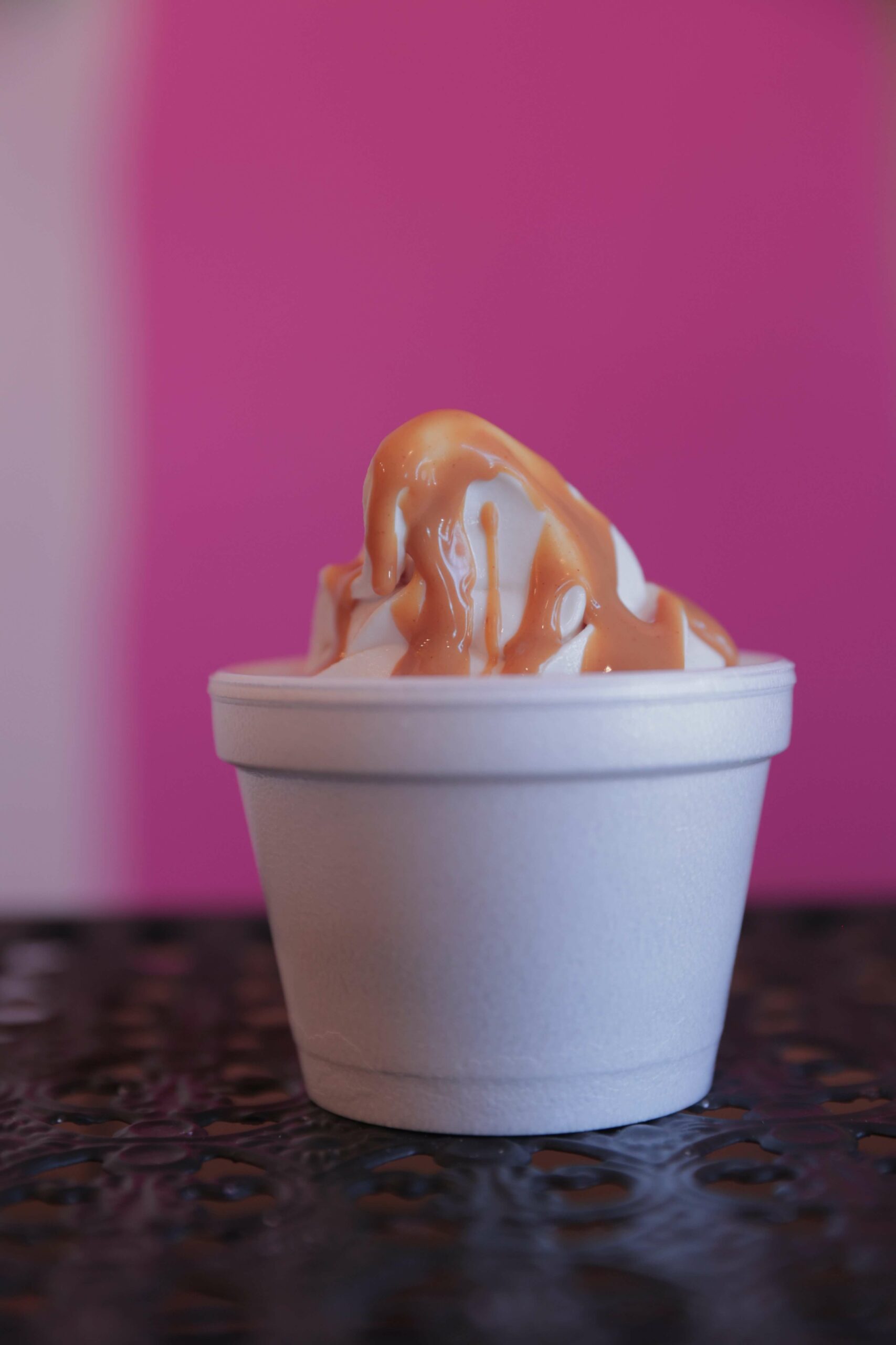 Vanilla soft serve ice cream from Gruto's with caramel drizzle on top, in a white cup